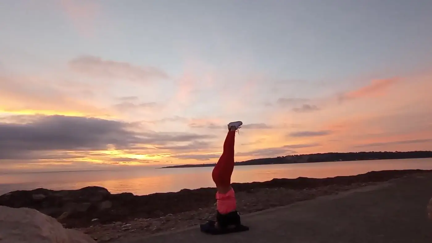 Posture sur la tête (Sirsasana) face à la mer au coucher du soleil
